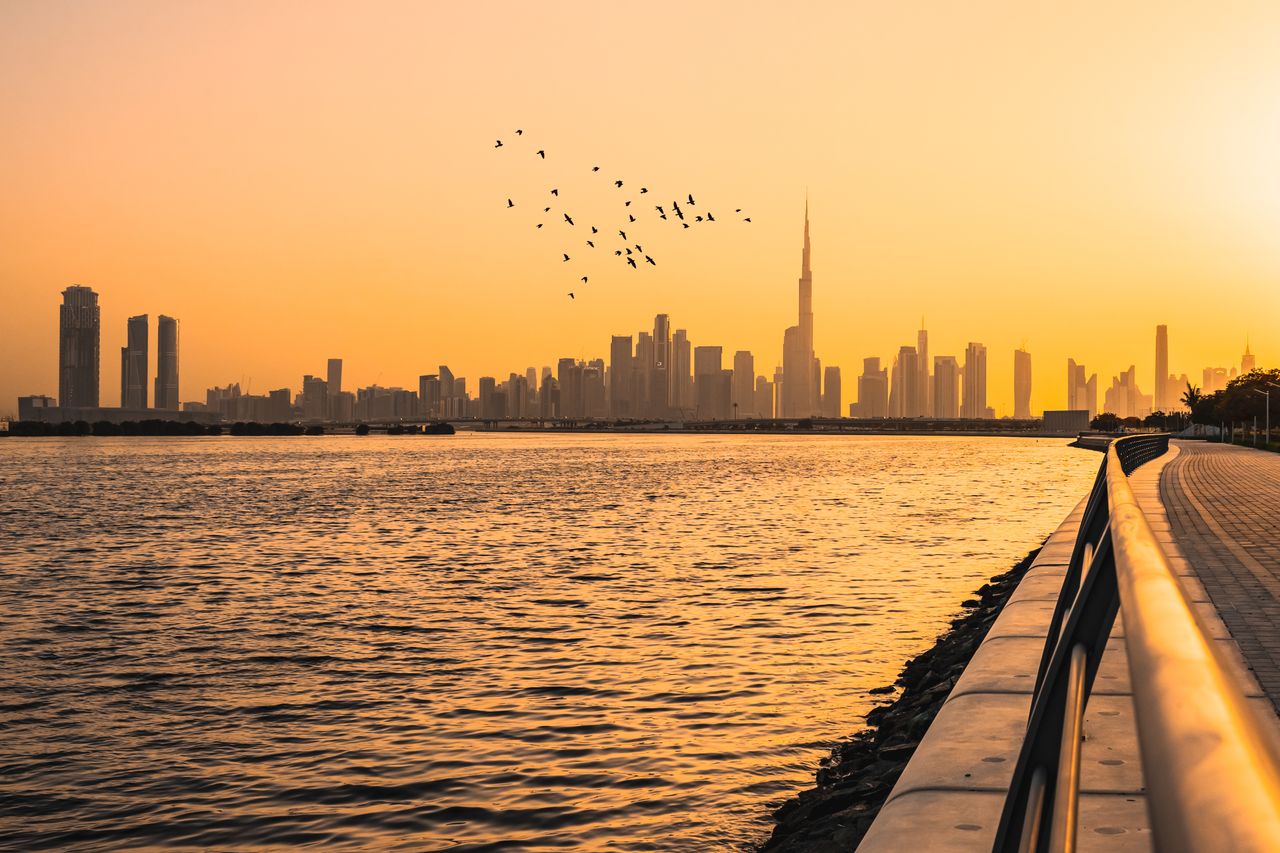 Captivating view of Dubai skyline with Burj Khalifa at sunset across the shoreline.